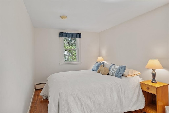 bedroom with baseboards, baseboard heating, and wood finished floors