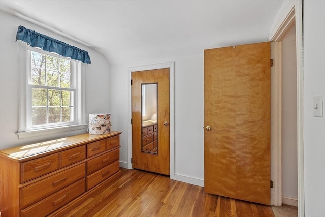 bedroom with baseboards, vaulted ceiling, and light wood-style floors