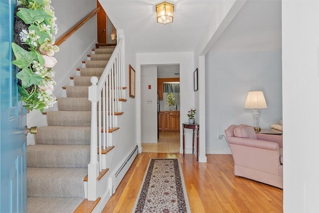 entrance foyer featuring baseboards, a baseboard radiator, light wood-style flooring, and stairway