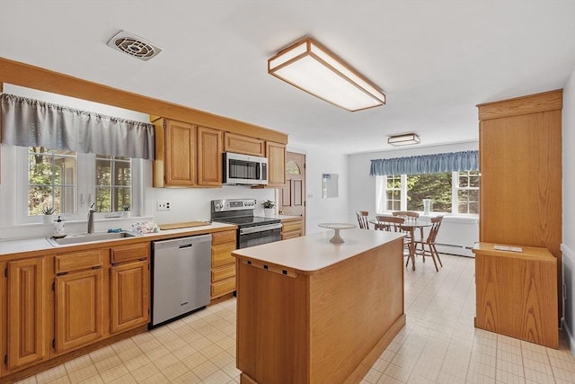 kitchen with visible vents, a center island, light countertops, a sink, and appliances with stainless steel finishes