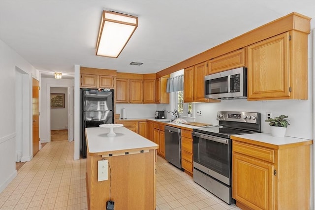 kitchen with a center island, light countertops, light tile patterned floors, a sink, and stainless steel appliances