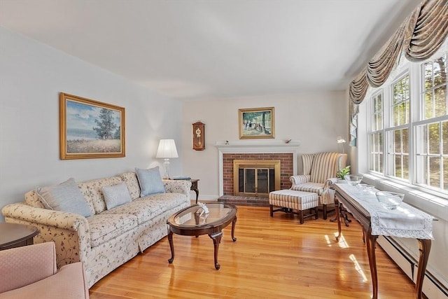 living area featuring a baseboard radiator, light wood finished floors, and a fireplace