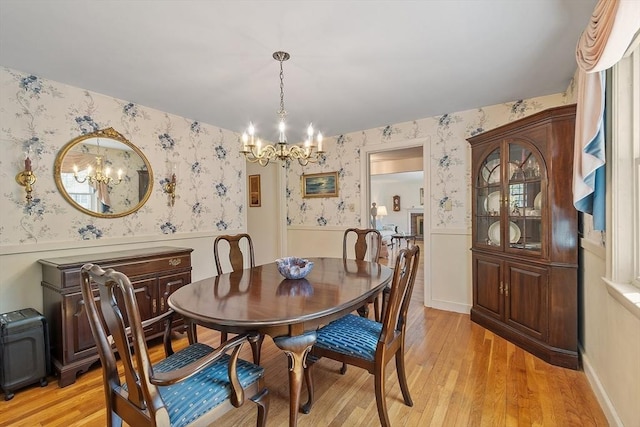 dining area with wallpapered walls, a notable chandelier, and wainscoting