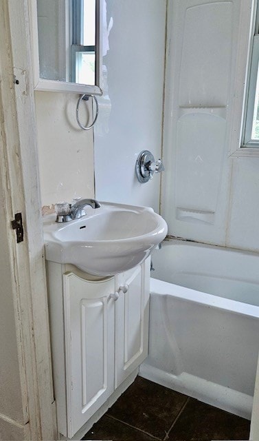 bathroom with a healthy amount of sunlight, tile patterned floors, a washtub, and vanity