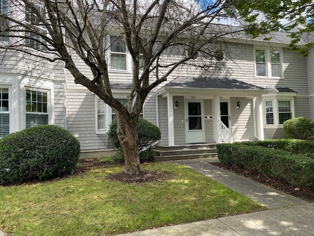 view of front of home featuring a porch, a front yard, and a shingled roof