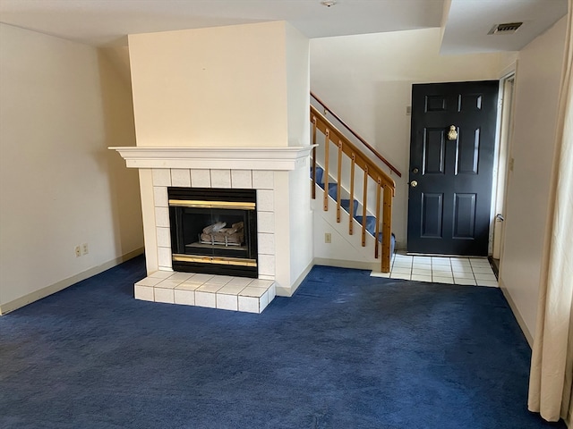 foyer with stairway, a tile fireplace, carpet flooring, and visible vents