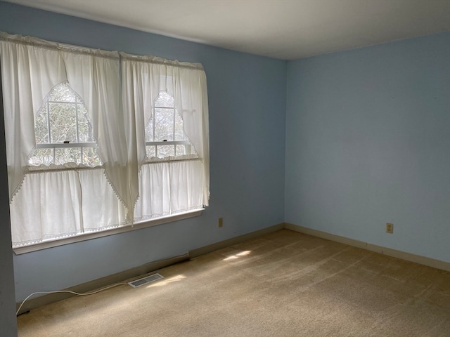 unfurnished room with carpet floors, baseboards, and visible vents