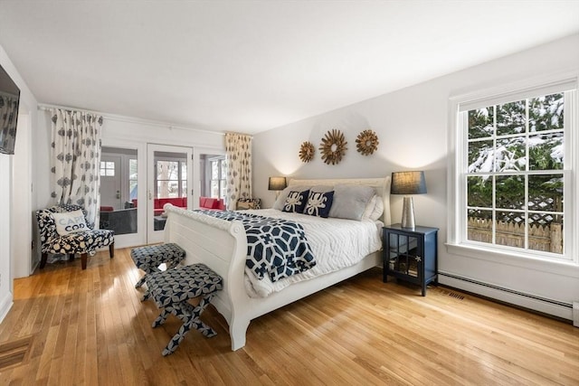 bedroom with access to outside, baseboard heating, visible vents, and wood-type flooring