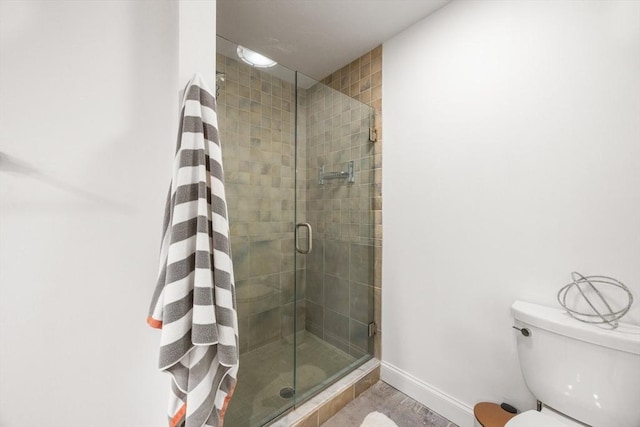 bathroom featuring a shower stall, toilet, and baseboards