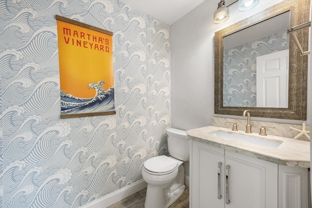 bathroom with toilet, vanity, and baseboards