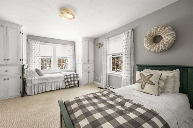 bedroom with multiple windows, light carpet, baseboards, and a baseboard heating unit