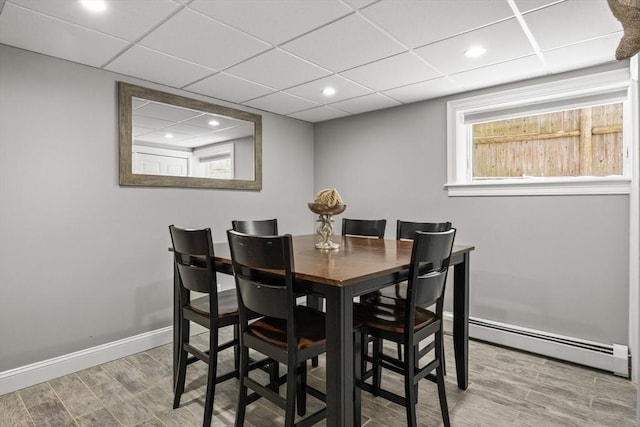 dining room with a drop ceiling, wood finished floors, recessed lighting, baseboards, and baseboard heating