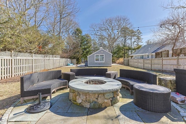 view of patio / terrace featuring an outbuilding, a fenced backyard, and an outdoor fire pit