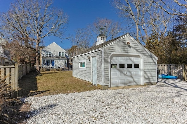 detached garage with gravel driveway and fence