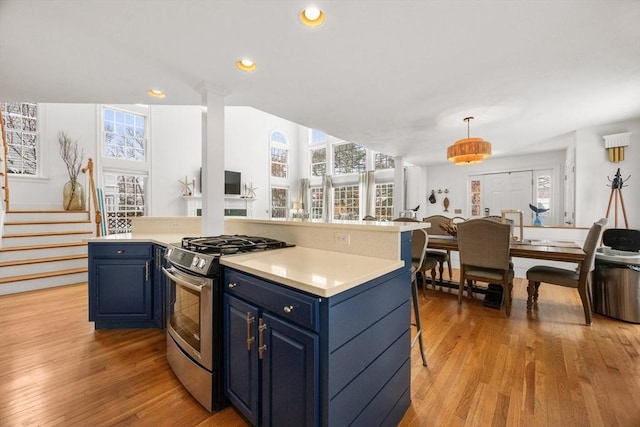 kitchen with light wood-style floors, stainless steel range with gas stovetop, blue cabinets, and open floor plan