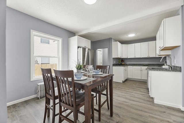 dining space featuring hardwood / wood-style floors, radiator heating unit, sink, and a textured ceiling