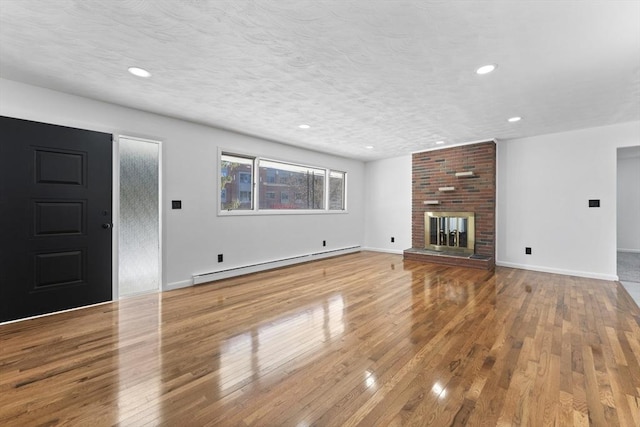 unfurnished living room featuring a baseboard radiator, a brick fireplace, a textured ceiling, and light hardwood / wood-style floors