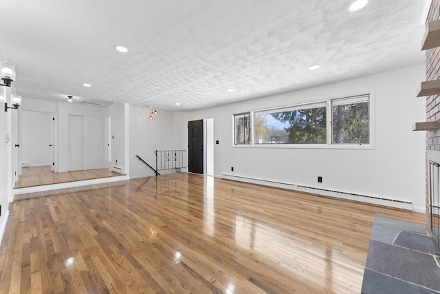 unfurnished living room featuring a baseboard radiator and hardwood / wood-style floors