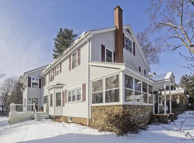 view of snow covered exterior with a sunroom