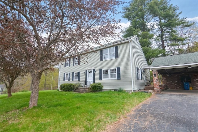 colonial home featuring a carport, a front yard, and aphalt driveway