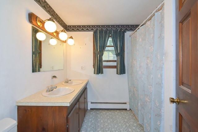 bathroom featuring a sink, baseboard heating, toilet, and double vanity