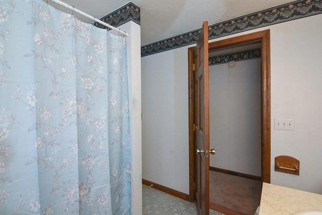 bathroom featuring baseboards and curtained shower