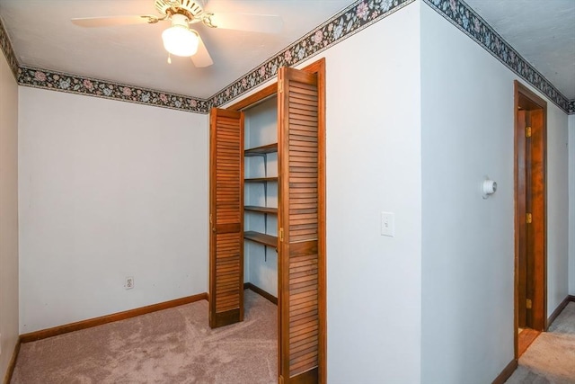 interior space with carpet floors, baseboards, ceiling fan, and a closet