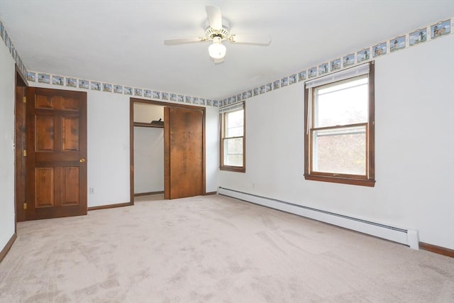 unfurnished bedroom with light colored carpet, baseboard heating, a ceiling fan, baseboards, and a closet