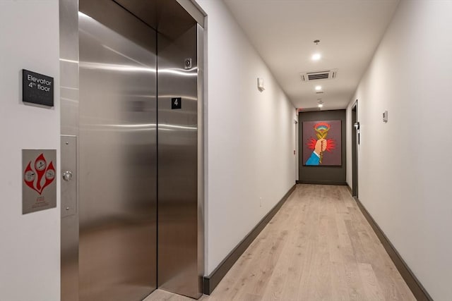 hallway featuring elevator and light hardwood / wood-style floors