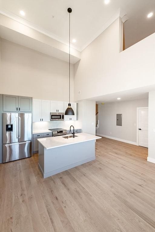 kitchen featuring hanging light fixtures, stainless steel appliances, sink, and an island with sink