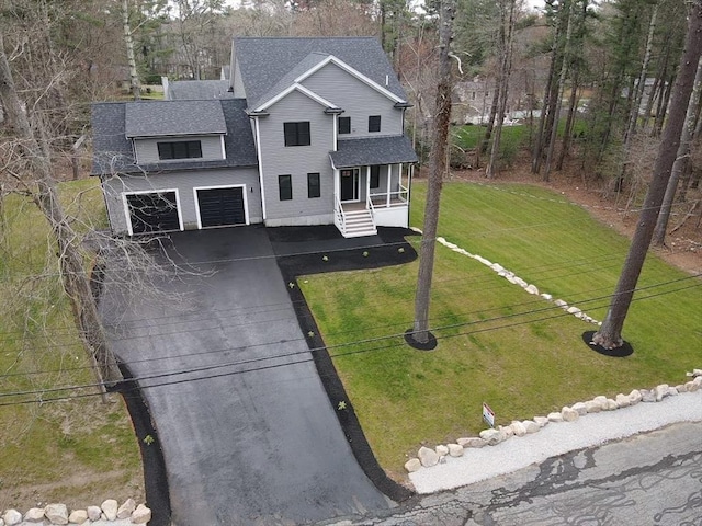 view of front facade with roof with shingles, a front lawn, a garage, covered porch, and driveway