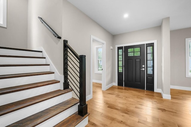 entryway with baseboards, light wood-style flooring, and stairway