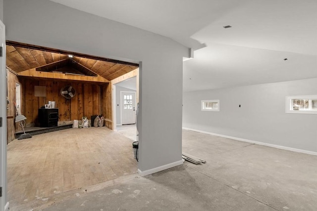 2 Britlees Way, Dudley, MA 01571 - unfurnished living room with vaulted ceiling, a wood stove, plenty of natural light, and wooden walls