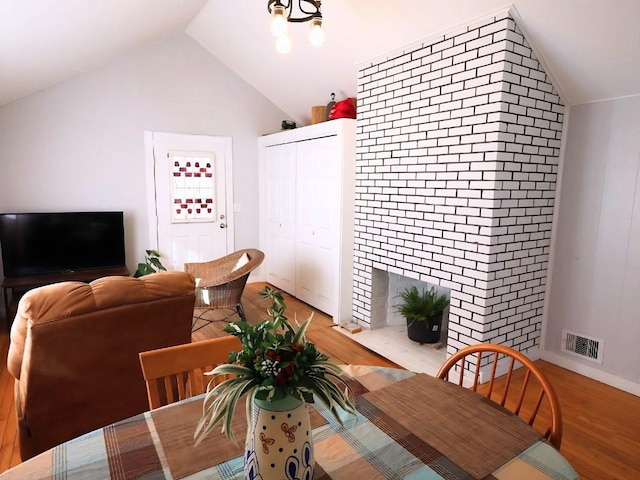 dining room with light wood-type flooring, visible vents, and vaulted ceiling