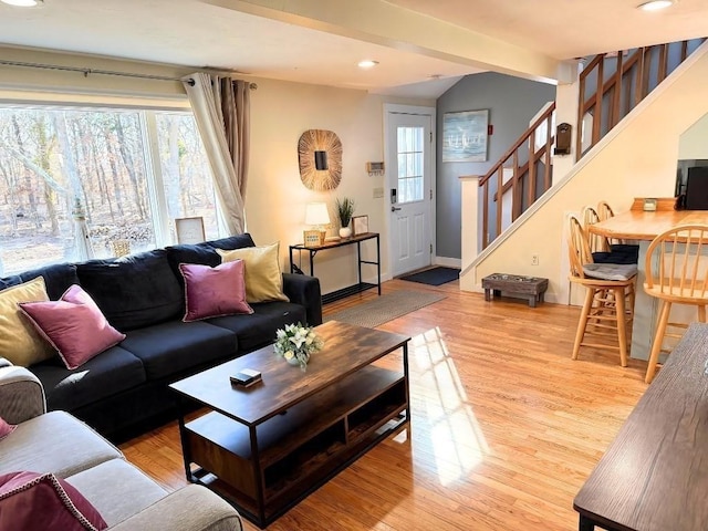 living area featuring light wood-style flooring, stairway, a wealth of natural light, and baseboards