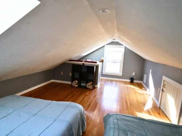 bedroom with lofted ceiling, baseboards, and wood finished floors