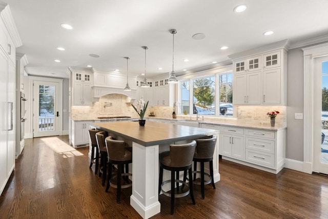 kitchen featuring glass insert cabinets, a breakfast bar, white cabinets, and crown molding