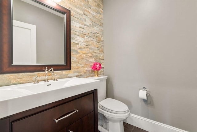 half bathroom with toilet, tile patterned flooring, baseboards, and vanity