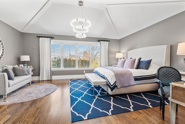 bedroom featuring a notable chandelier, vaulted ceiling, baseboards, and wood finished floors