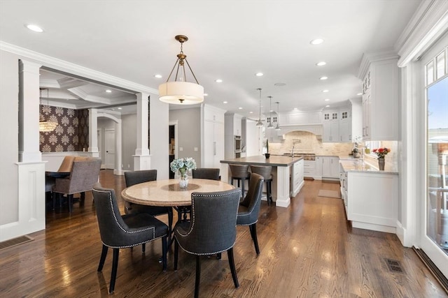 dining room with arched walkways, crown molding, dark wood finished floors, and ornate columns