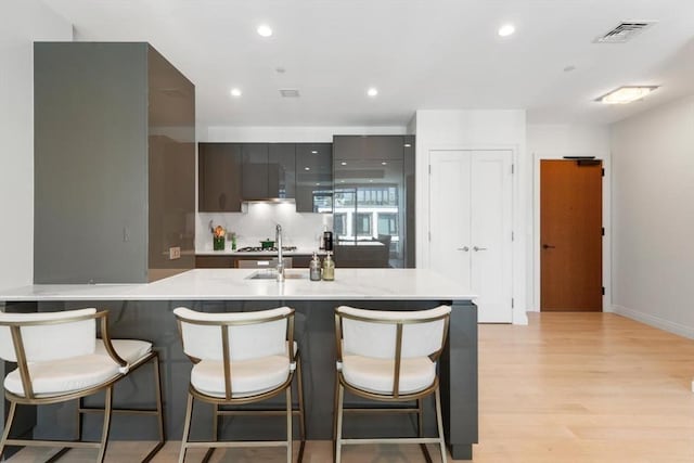 135 Seaport Blvd Unit 1901, Boston, MA 02210 - kitchen featuring light wood-style floors, a kitchen bar, recessed lighting, modern cabinets, and stainless steel gas stovetop