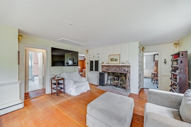 575 Nauset Rd, Eastham, MA 02642 - living area featuring a baseboard heating unit, a brick fireplace, and light wood-style flooring