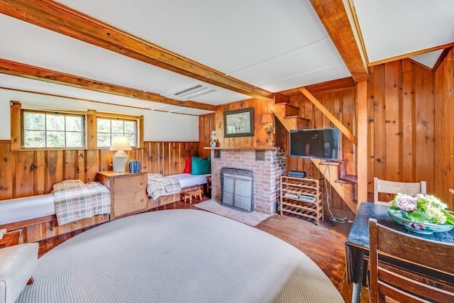 575 Nauset Rd, Eastham, MA 02642 - bedroom with wooden walls, beamed ceiling, wood finished floors, a brick fireplace, and a wainscoted wall