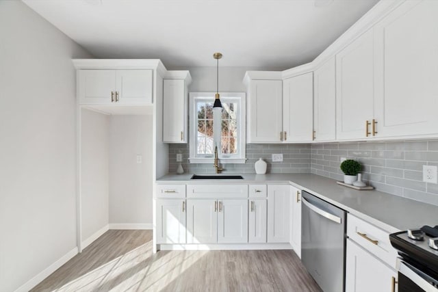 kitchen with pendant lighting, sink, white cabinets, stainless steel dishwasher, and light hardwood / wood-style flooring