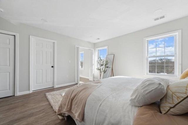 bedroom with dark wood-type flooring and multiple windows