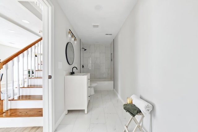 full bathroom with tiled shower / bath, vanity, and toilet