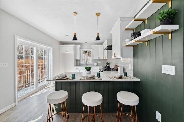 kitchen featuring white cabinetry, pendant lighting, kitchen peninsula, and a breakfast bar