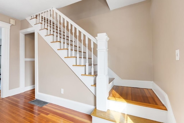 stairs with visible vents, baseboards, and wood finished floors