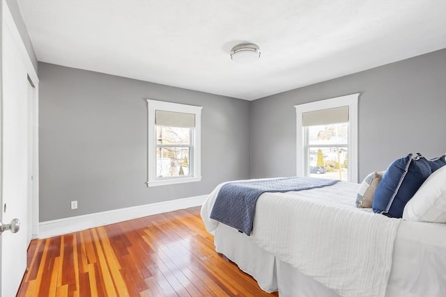 bedroom featuring multiple windows, baseboards, and wood-type flooring