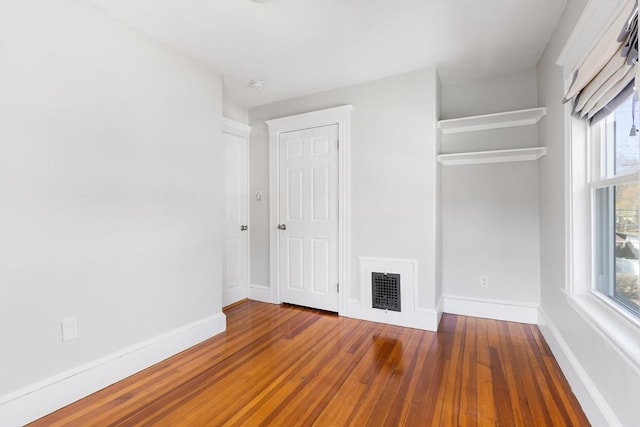 unfurnished bedroom with visible vents, baseboards, and hardwood / wood-style flooring